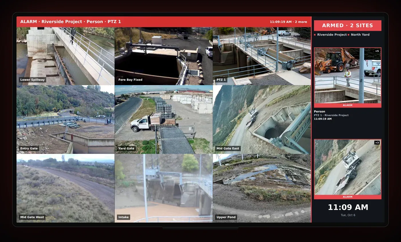 A TV showing a live camera wall with an alarm banner and alarm cards